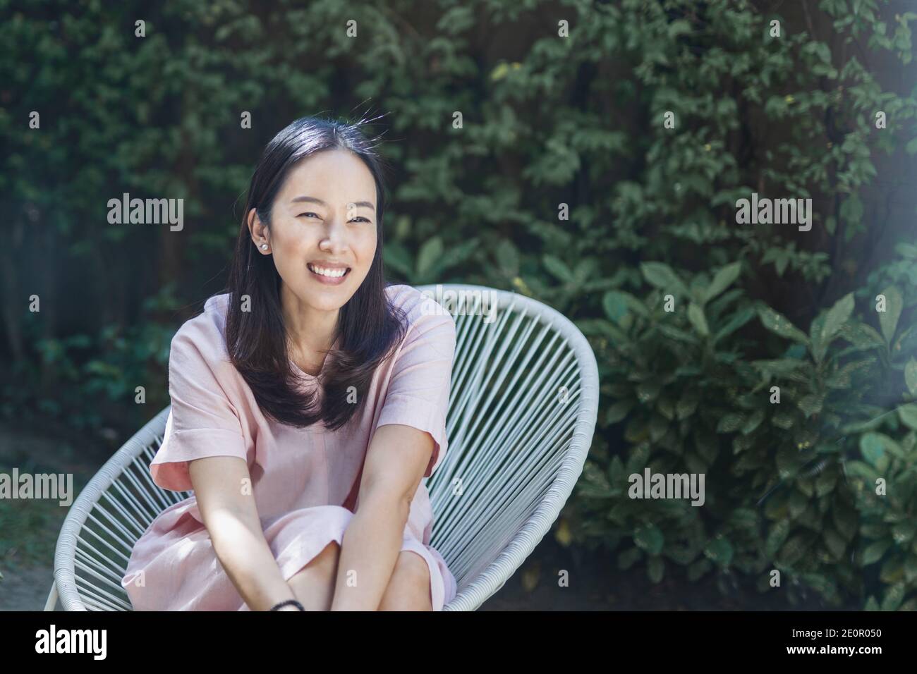 Portrait of woman sitting in the garden and smiling Stock Photo - Alamy
