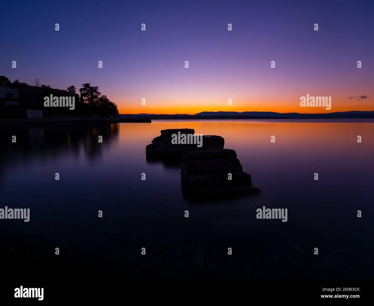 Sunset serene scenery rocks on calm sea surface Malinska on island Krk in Croatia Europe Stock Photo