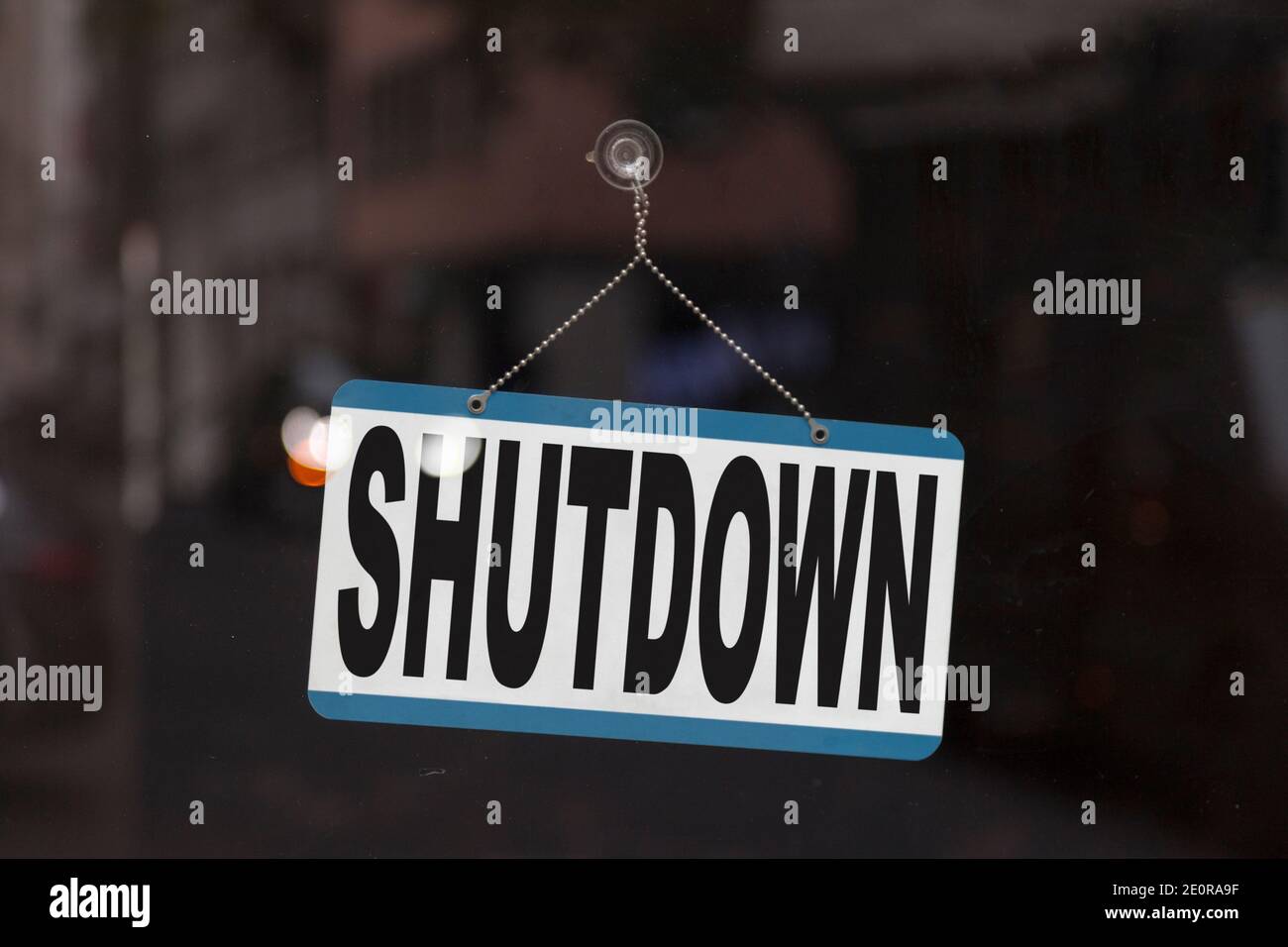 Close-up on a closed sign in the window of a shop displaying the message: Shutdown. Stock Photo