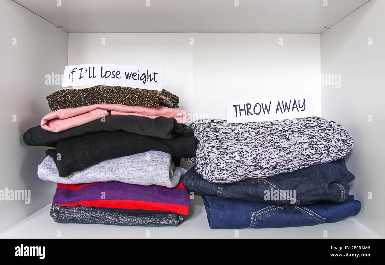 Clothes sorting in home wardrobe on white shelf background. If I'll lose weight, Throw away paper notes. Stock Photo