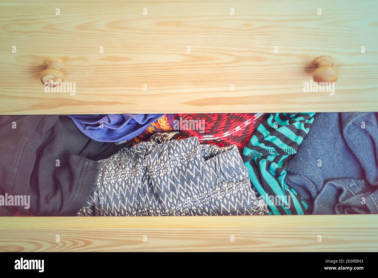 Open light wooden dresser drawer with colorful clothes. Stock Photo