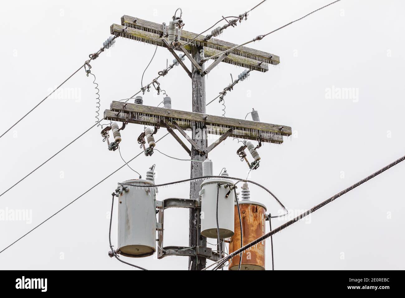 Ice on electrical utility pole and power line from freezing rain. Concept of winter storm and power outage. Stock Photo