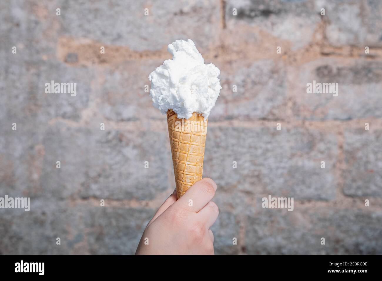 A Hand holding lemon flavored artisan ice cream. Lemon ice cream served in a waffle cone. Home