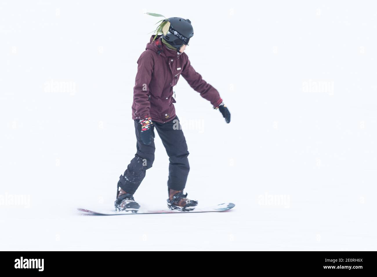A snowboarder wears a leaf in his helmet as he skis down the slopes of Niseko, Hokkaido, Japan. Stock Photo