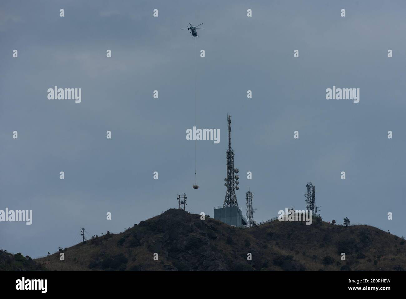 A helicopter drops construction materials on the top of Kowloon Peak, in Hong Kong. Stock Photo