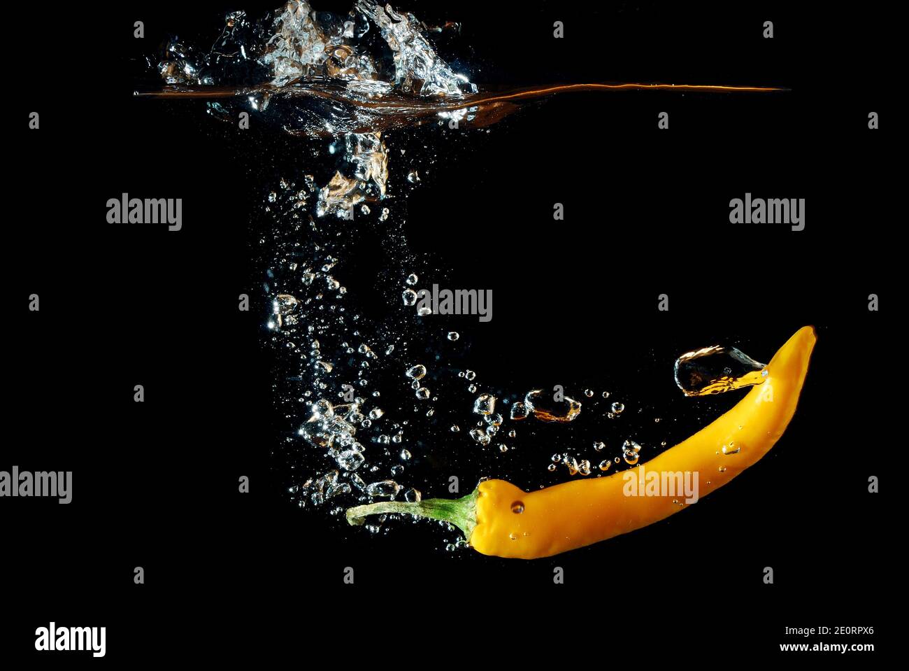 fresh yellow chilli pepper falling in water and injected and produced ...
