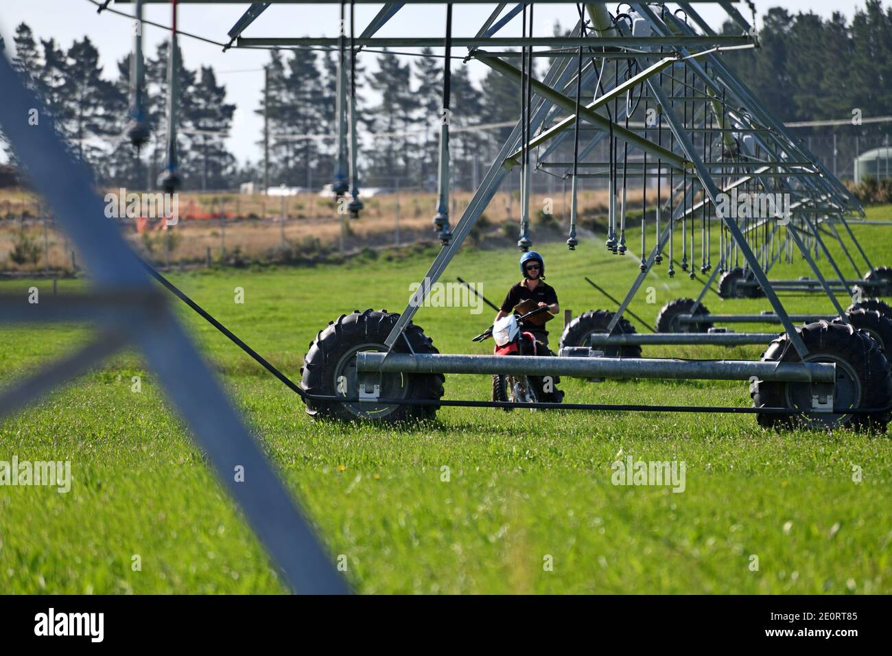 A farmer on a motorcycle checks out his irrigation equipment in Canterbury, New Zealand Stock Photo