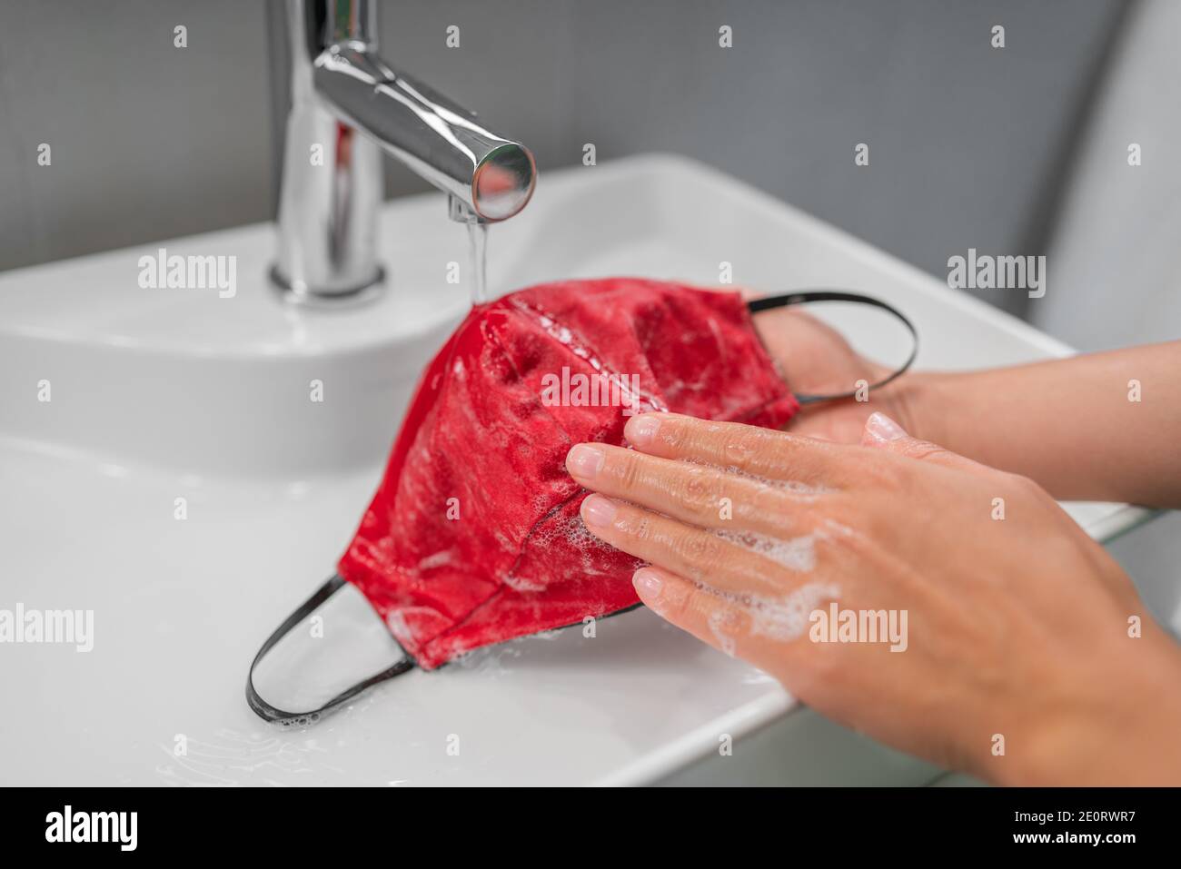 Washing cloth mask by hand after one use. Corona virus preventive face covering cleaning at home in sink Stock Photo