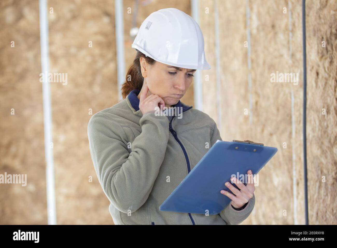 female builder reading clipboard with confused expression Stock Photo