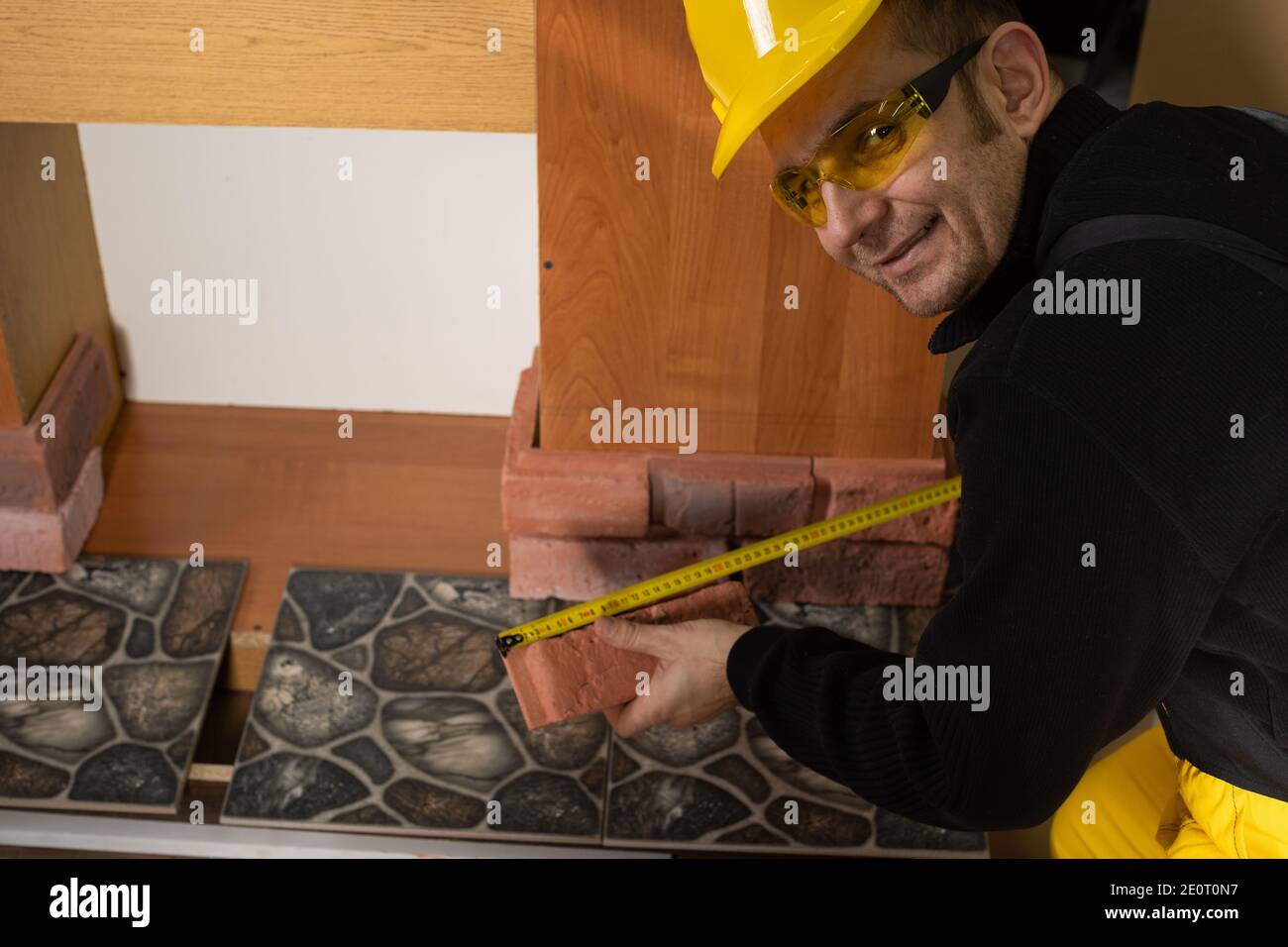 While measuring with a pull-out measure, a manual worker found time to smile and enjoy the job he is doing. Stock Photo