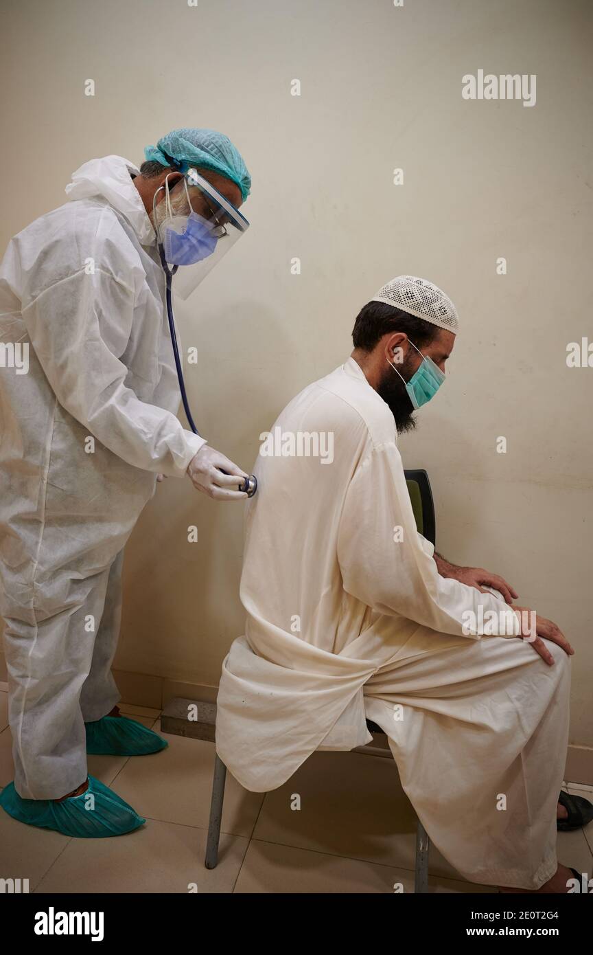 Amidst the coronavirus pandemic that continues to rise in the country rapidly, Dr. Saeed-ur-Rehman, dressed in full PPE gear diagnoses a TB patient who recently contracted COVID-19, at a community health centre in Shiri Jinnah neighbourhood in Karachi, the main port city of Pakistan. Stock Photo