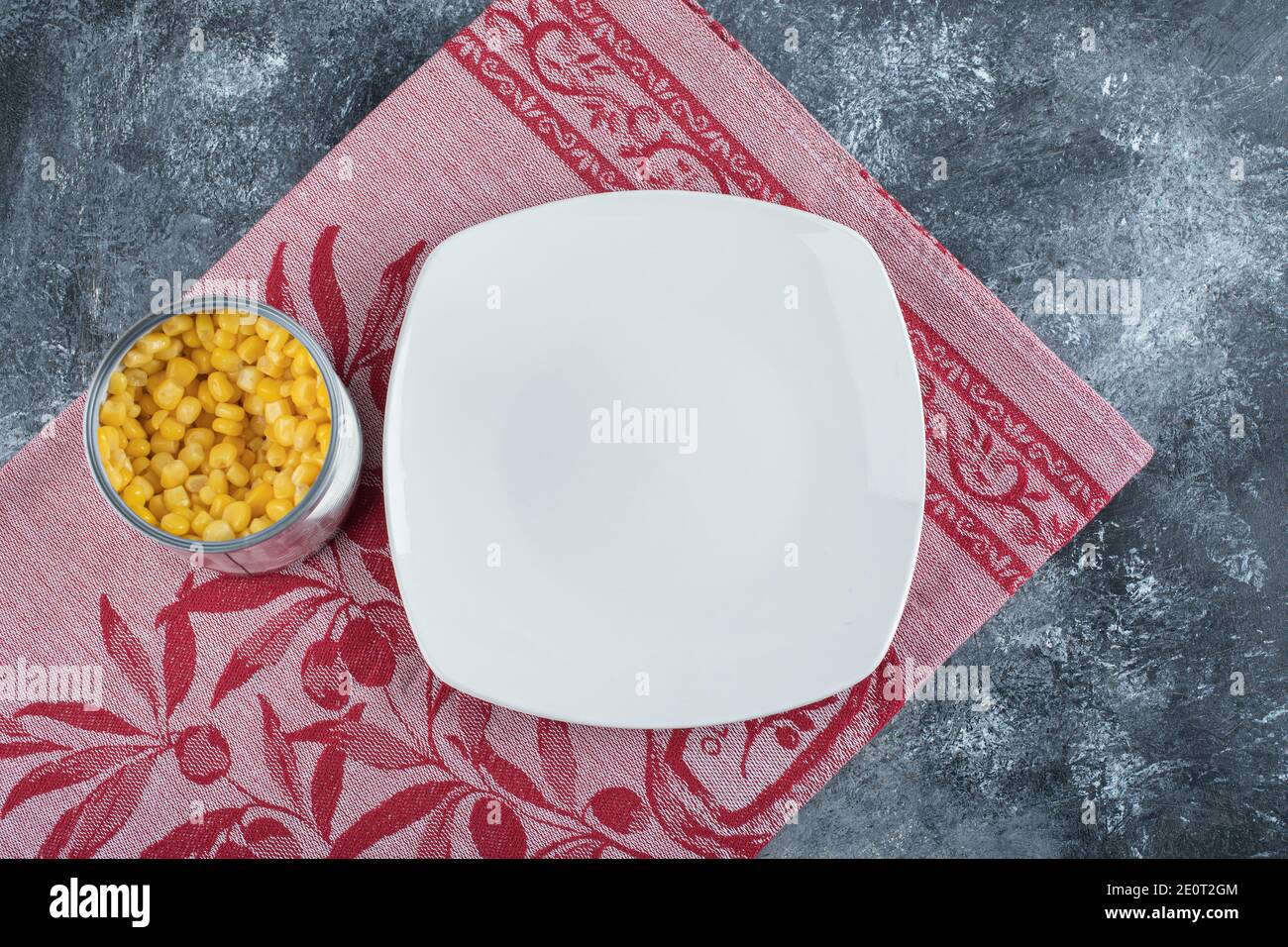 A can full of popcorn seeds with empty plate on a tablecloth Stock Photo