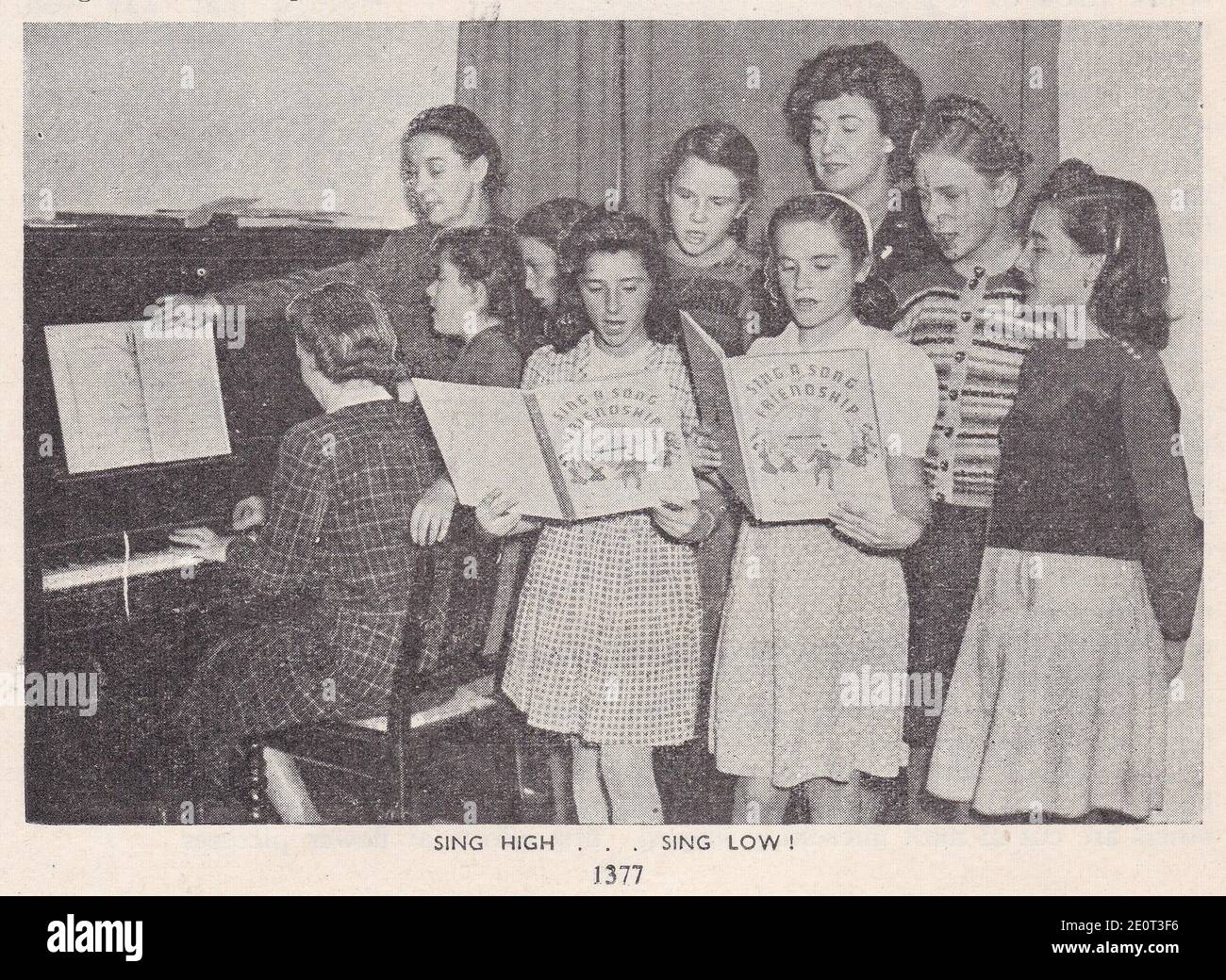 Vintage photo of school children singing around a piano. Stock Photo