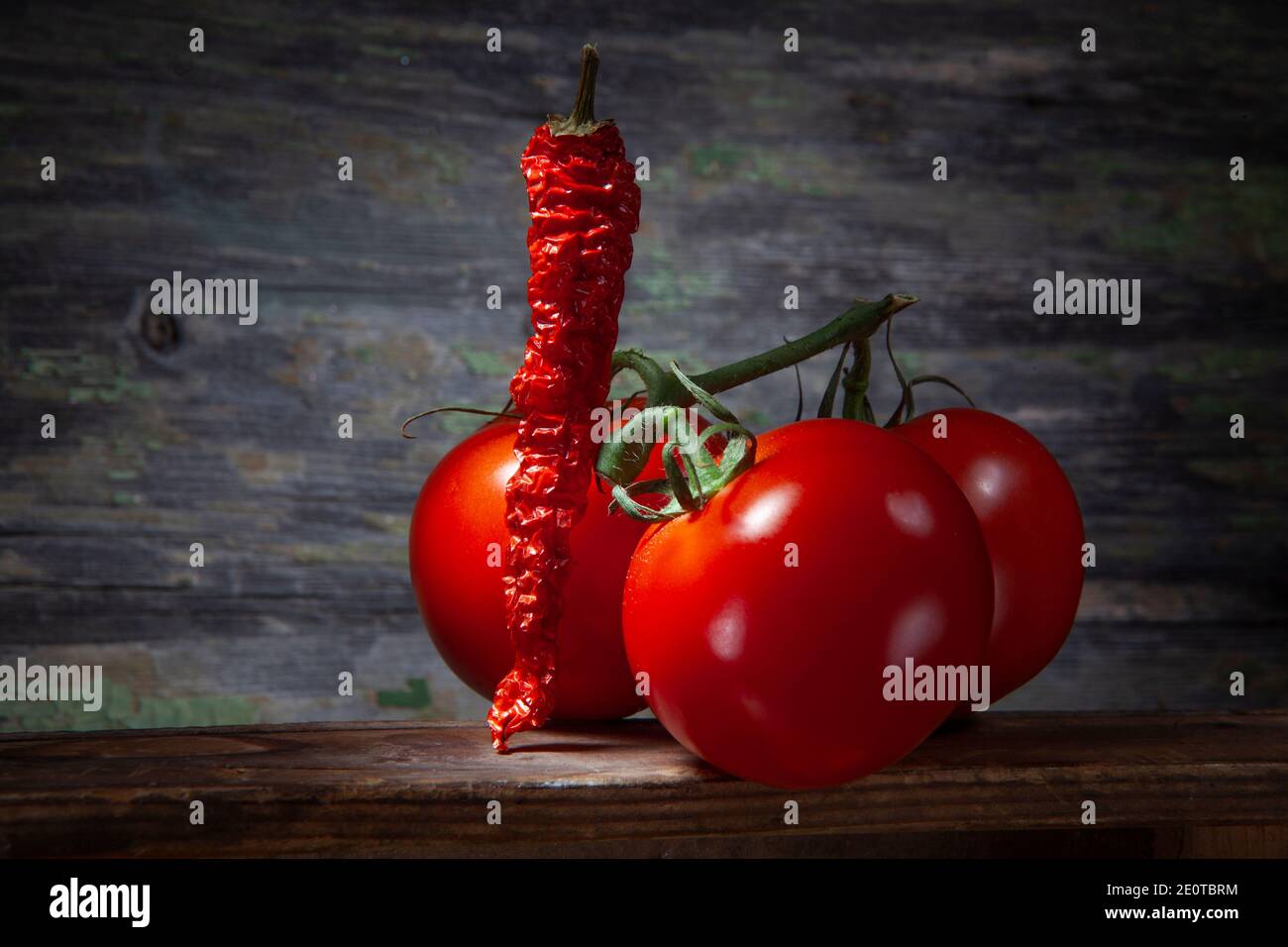 Crushed Red Hot Pepper with Three Tomatoes. On Wooden Background. Stock Photo