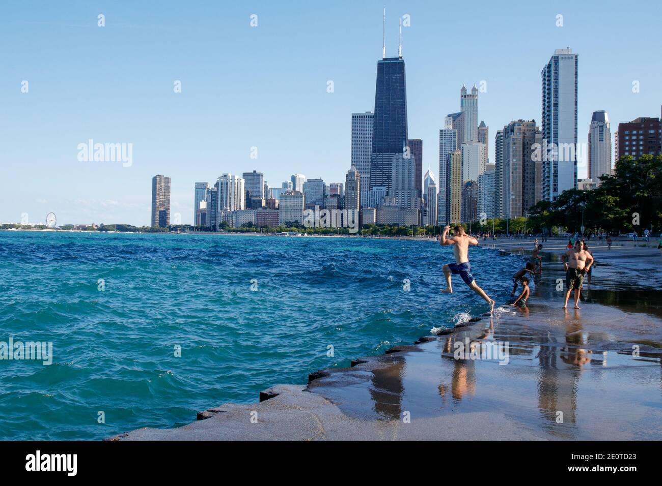 Chicago lakefront near North Avenue Beach. Young man jumping from seawall into lake. Stock Photo