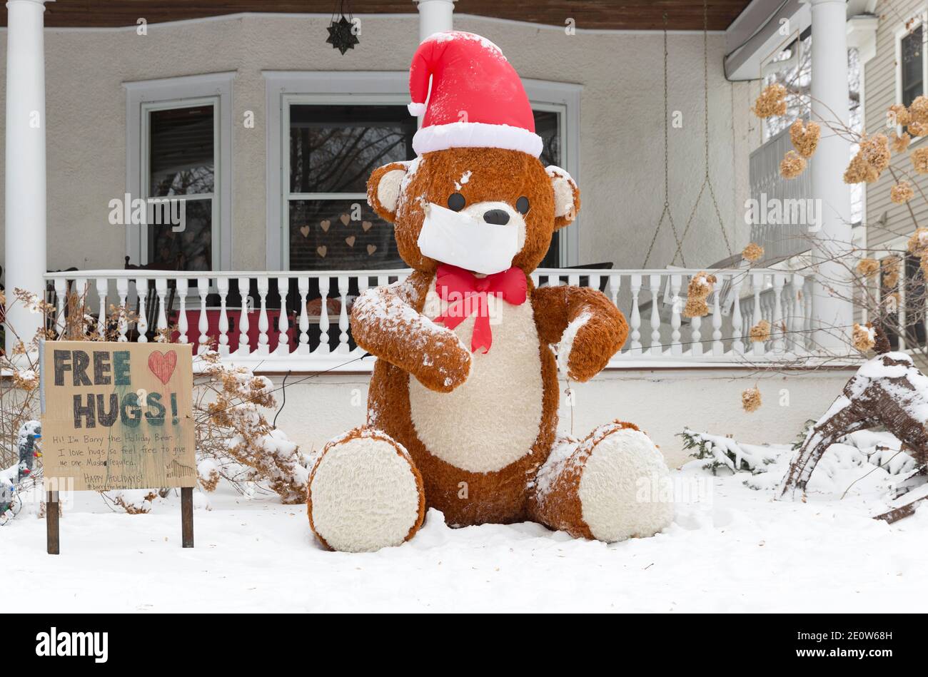 A Christmas yard display with a large teddy bear advertising free hugs during the Covid-19 pandemic of 2020 Stock Photo
