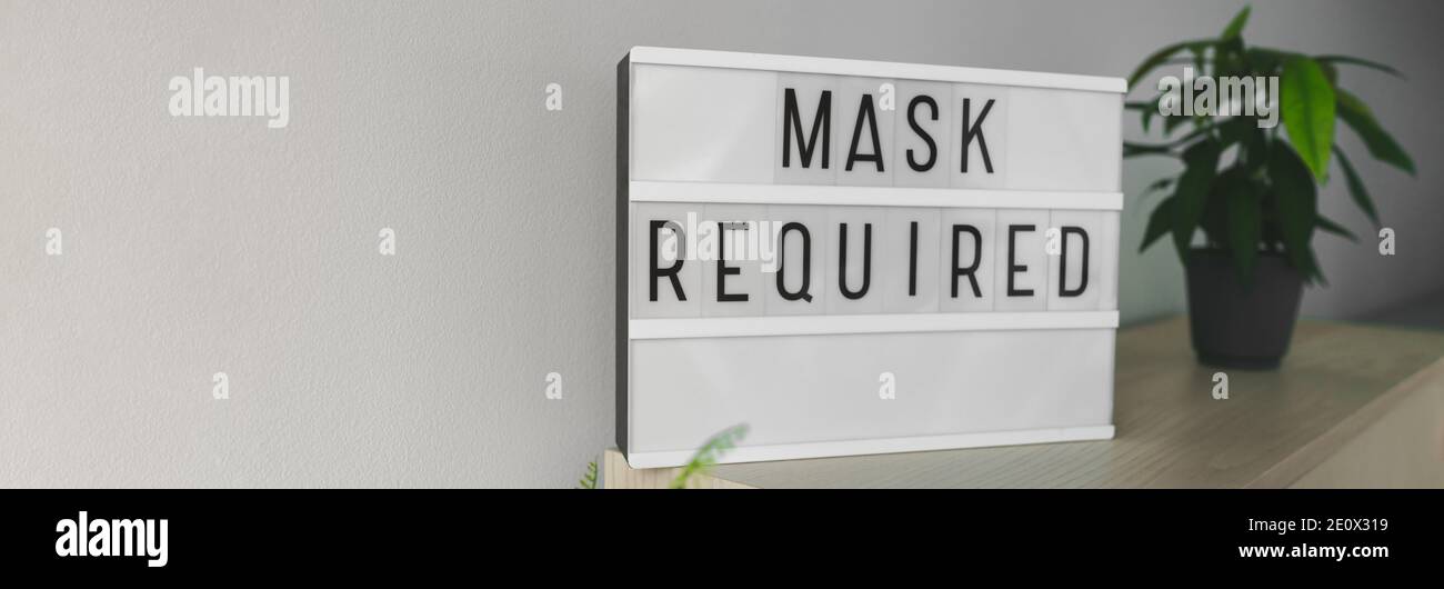 Business sign MASK REQUIRED banner panorama. Coronavirus store preventive measure asking to wear mandatory mask at indoor public spaces. Background Stock Photo