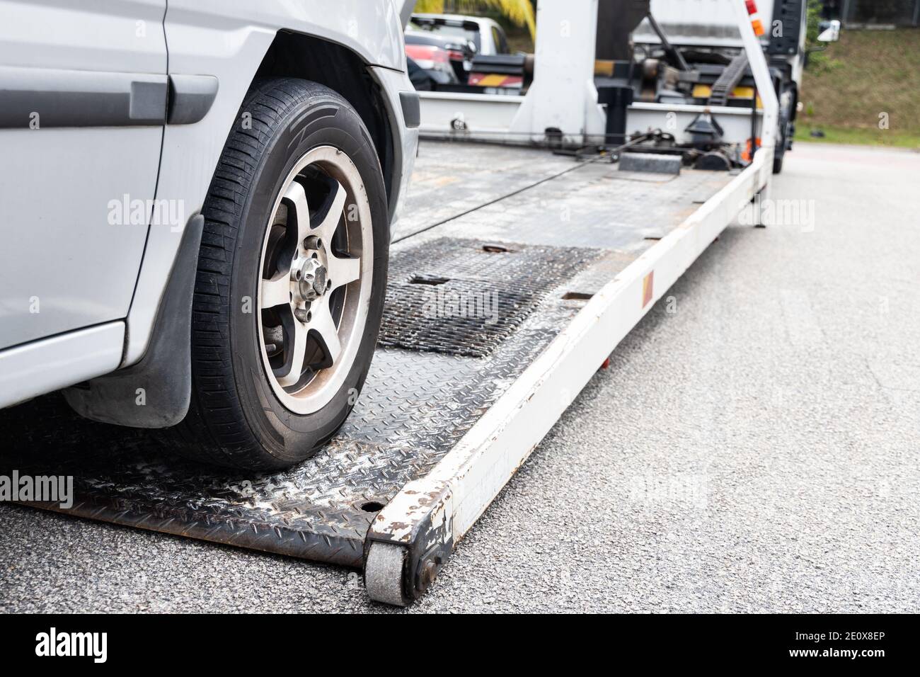 Cable attached to broken down car being pulled onto tow truck Stock Photo
