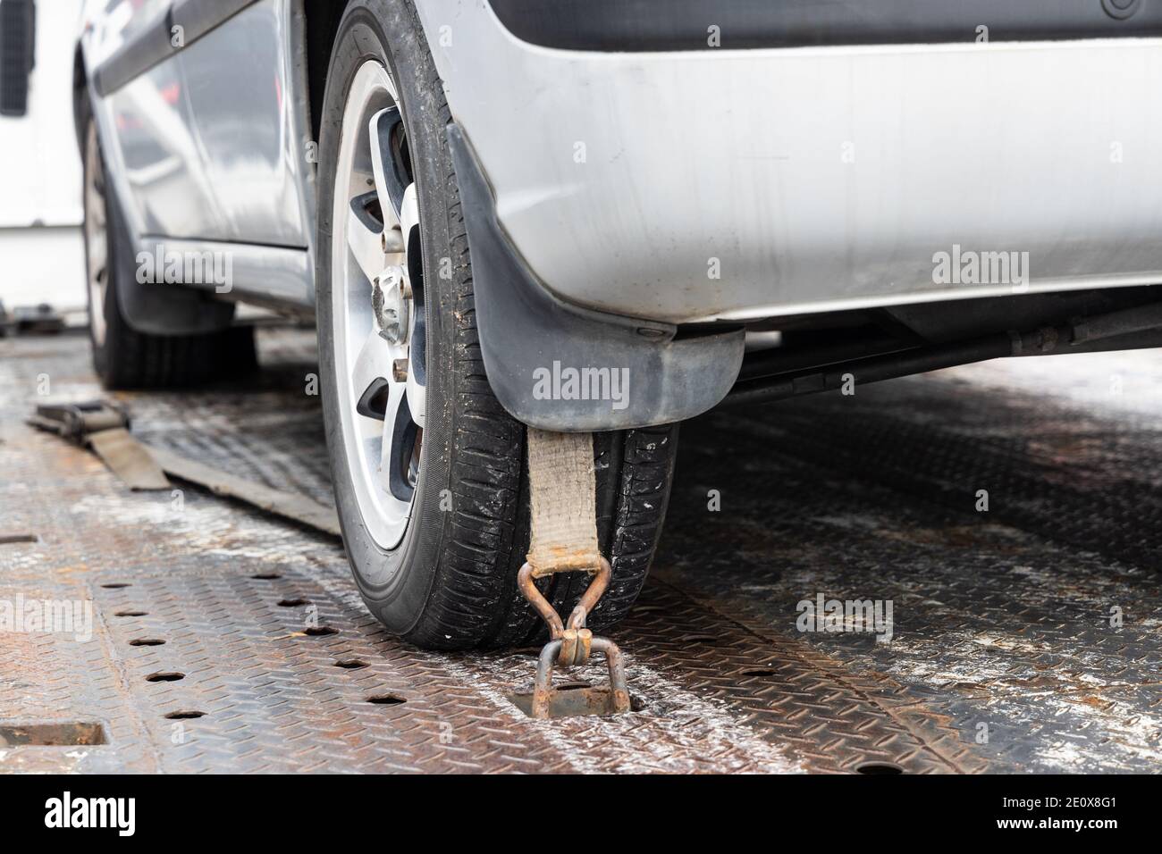 Close-up of car wheel tied with safety harness on flatbed tow truck Stock Photo