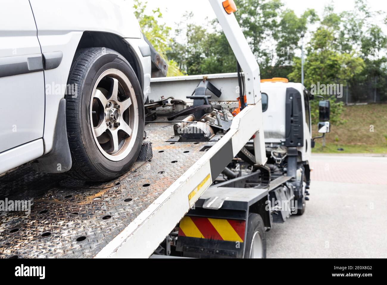 Cable attached to broken down car being pulled onto tow truck Stock Photo