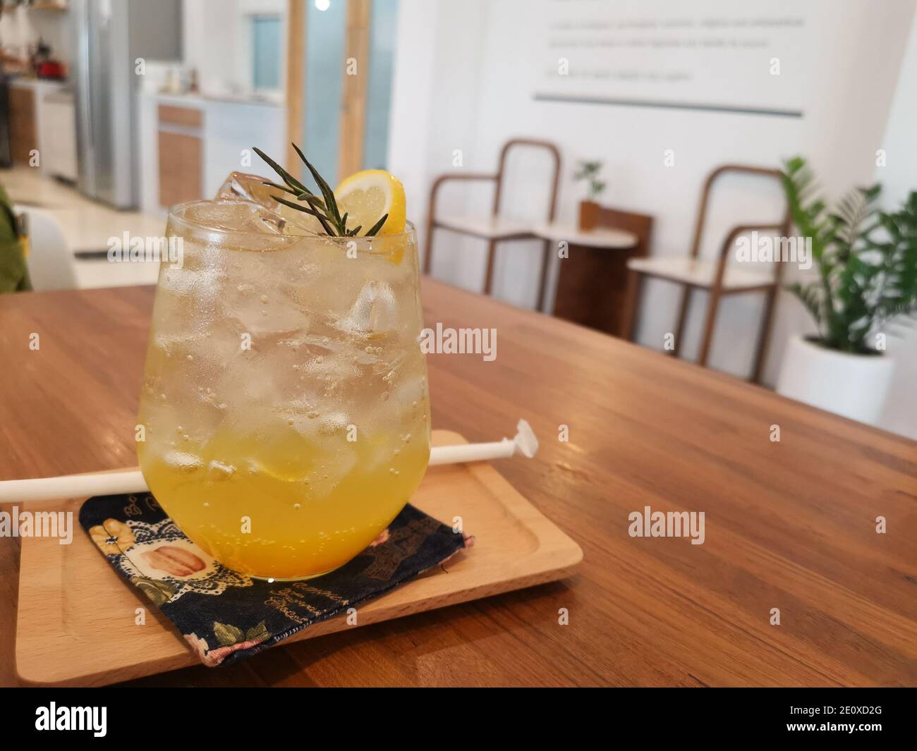 Yuzu orange drink with soda with ice. The drink splits the orange juice and soda into two different colors. The background is a blurry cafe. Stock Photo