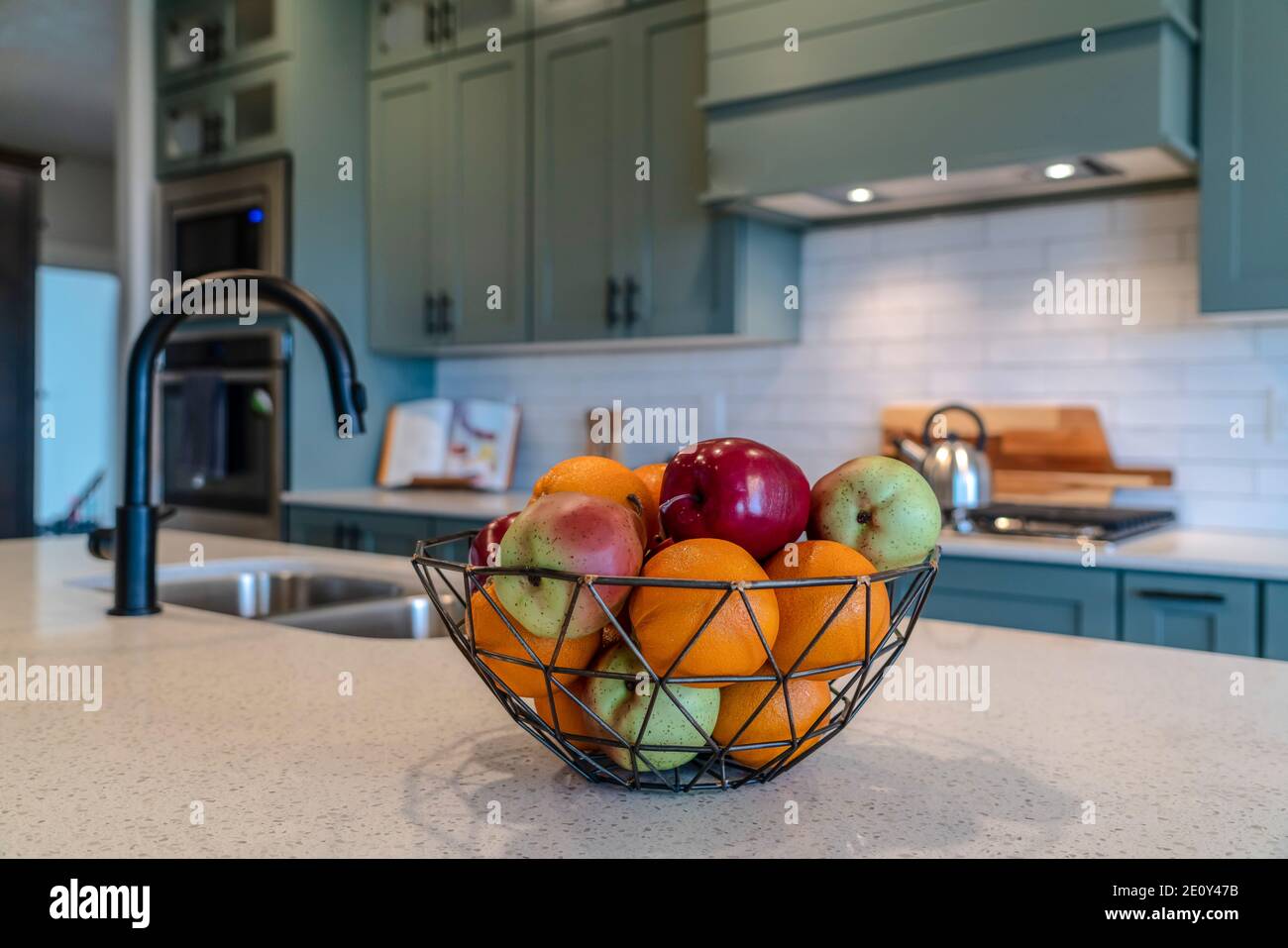 Fresh fruits inside wire basket on kitchen island with sink and curved