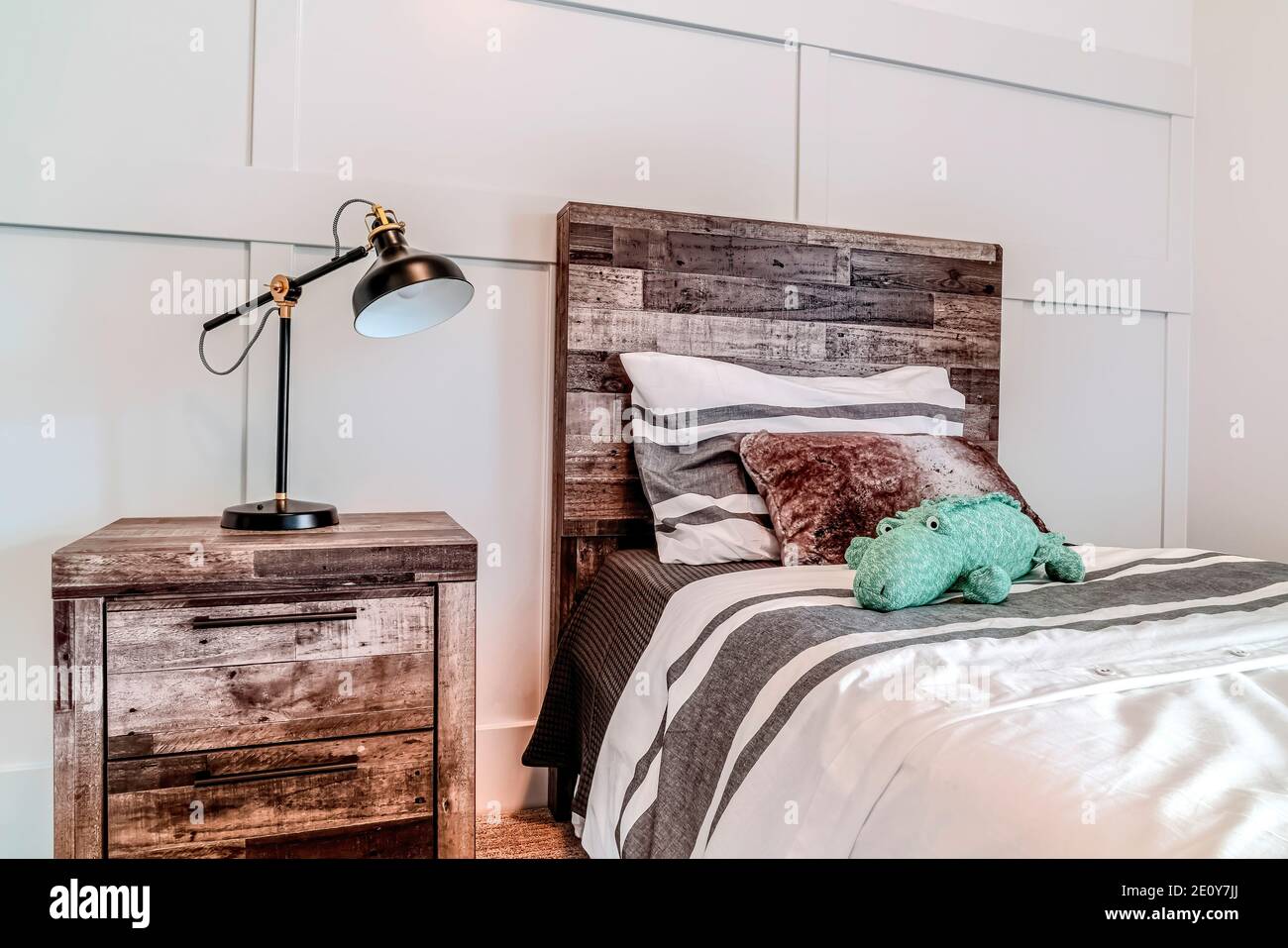 Lamp on side table beside bed with wooden headboard against panelled wall Stock Photo Alamy