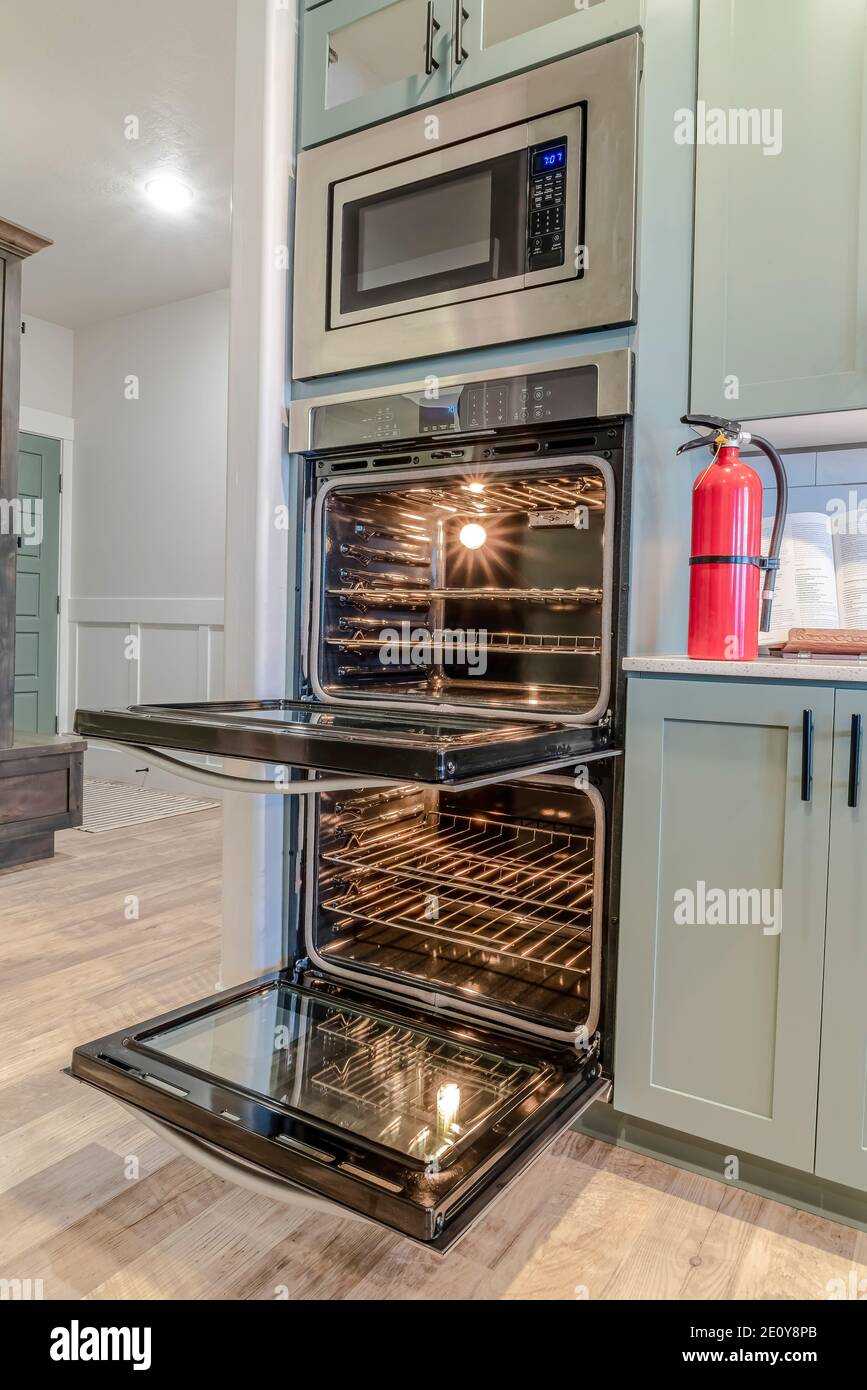 Oven microwave and fire extinguisher inside the kitchen with built in cabinets Stock Photo