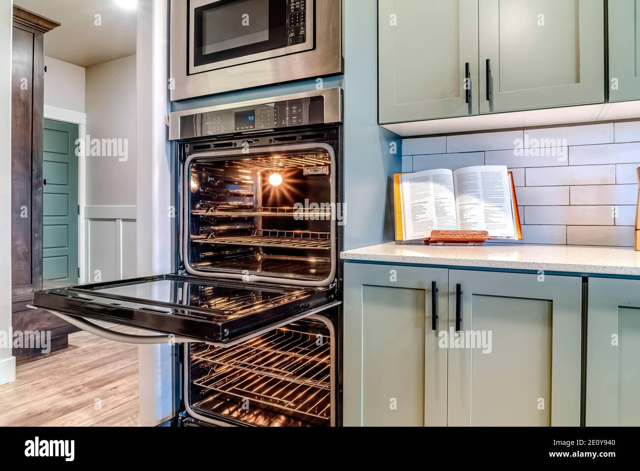 Oven and microwave inside the modern kitchen with built in cabinets and cookbook Stock Photo