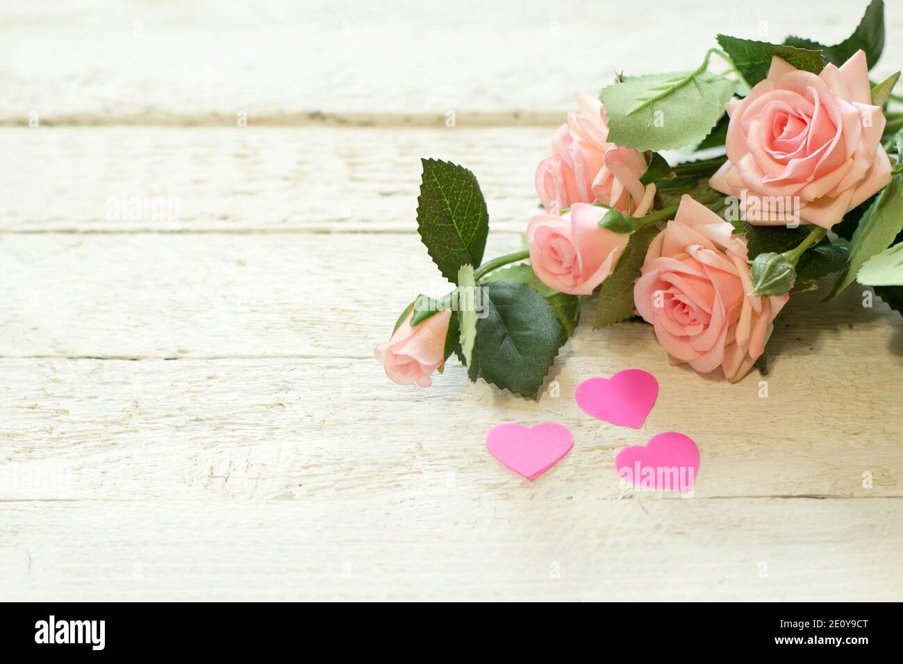 bouquet of small pink roses lying on white textured table with hearts Stock Photo
