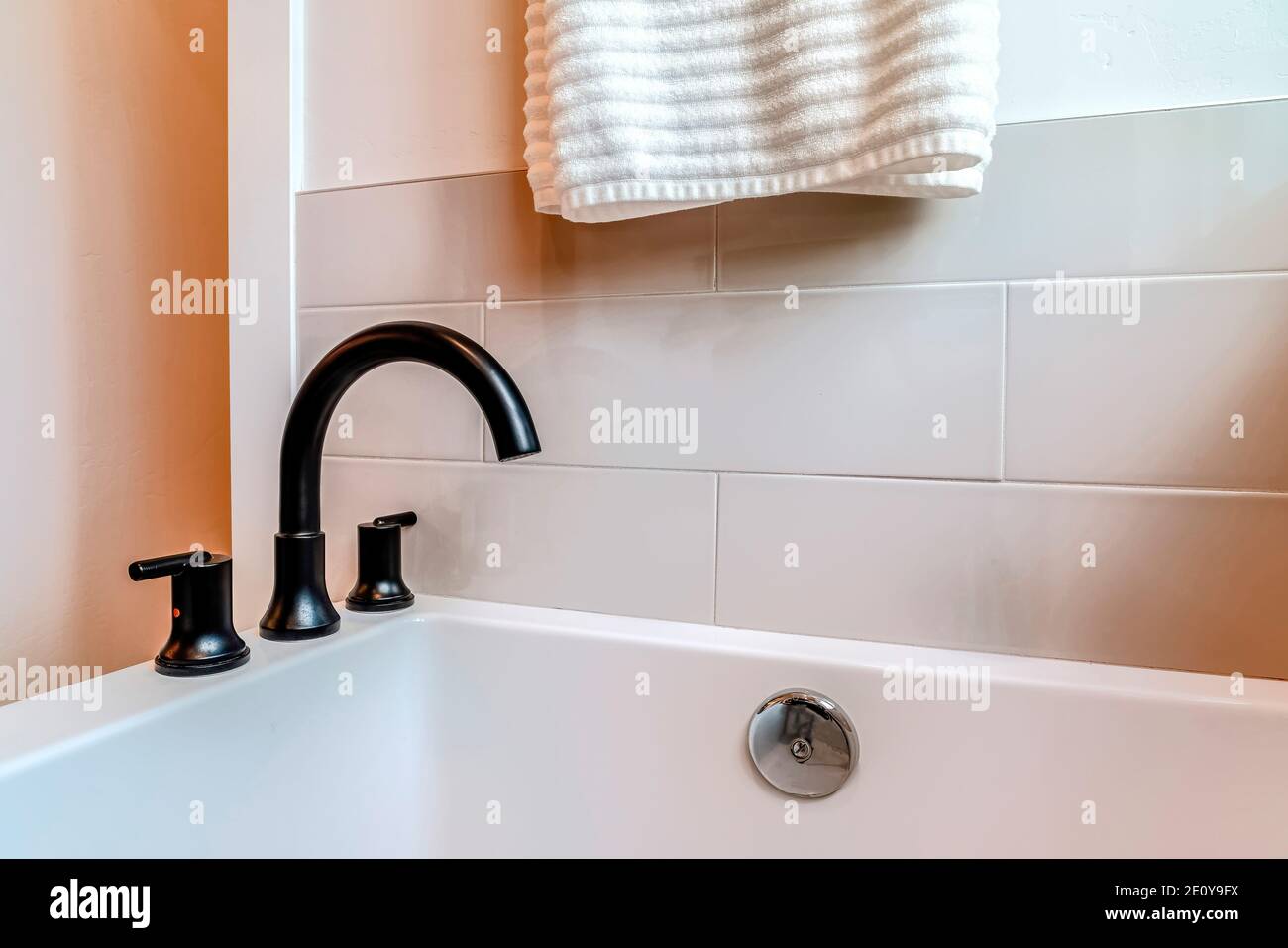Close up view of black gooseneck faucet on the rim of a bathtub inside