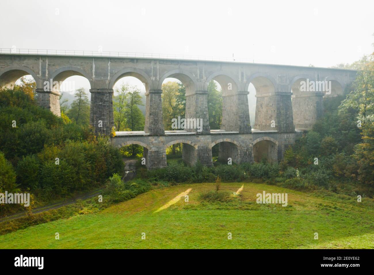 An two-tiered aqueduct or arched bridge in the terrain with high trees and beautiful landscape at sunlight. Stock Photo