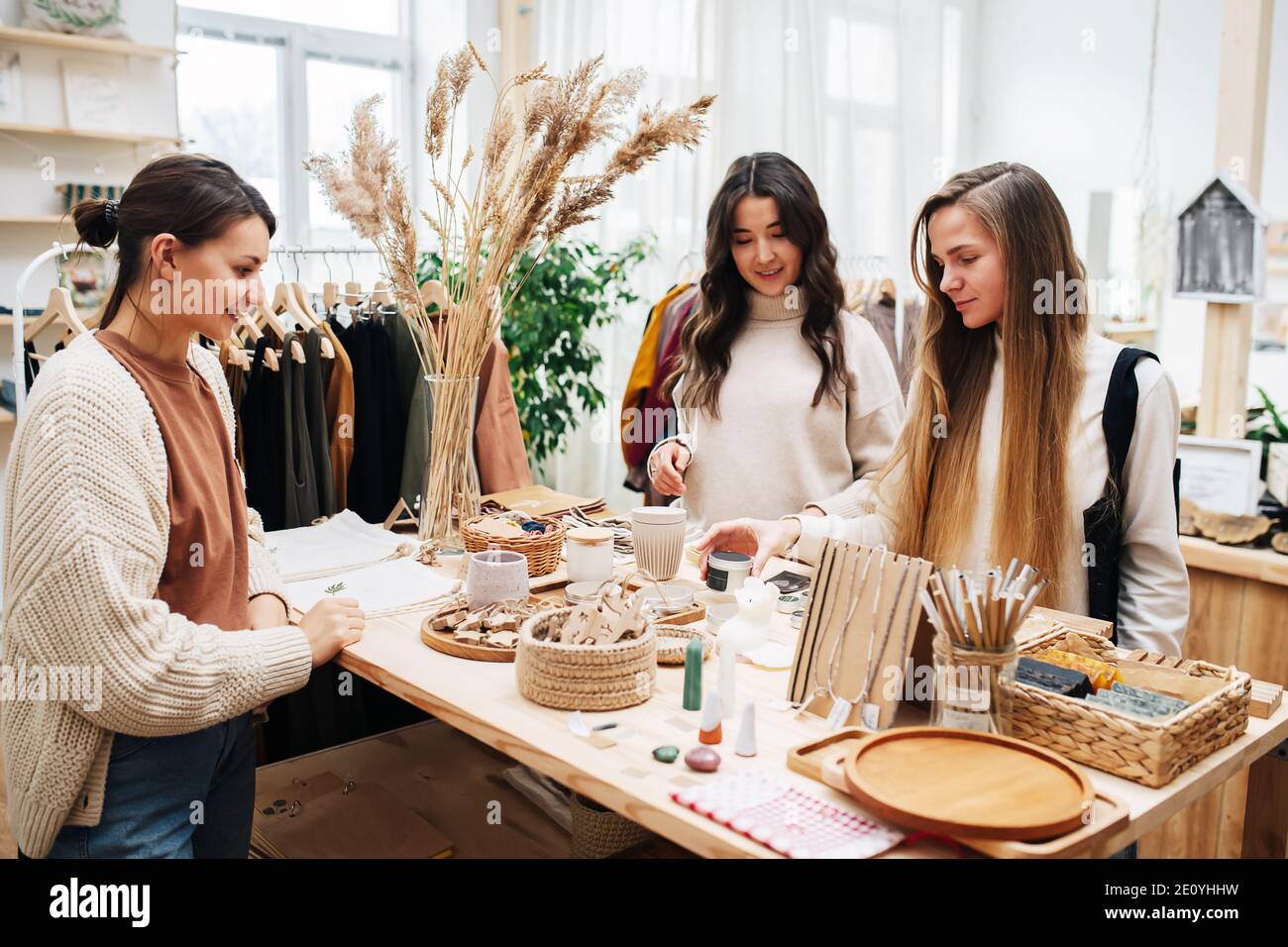 Chatting women in eco shop picking and discussing various cosmetic products Stock Photo