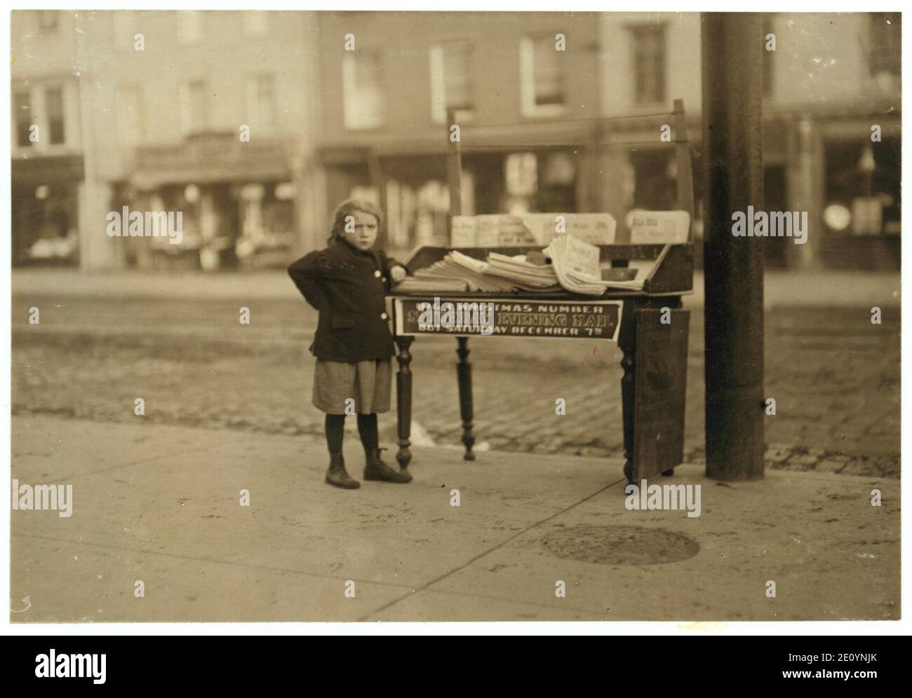 Little girl, apparently 6 yrs. old - but didn't know her name or age - tending stand at Washington and 3rd St. for older sister (-3234). Saloon on corner. 3 P.M. Stock Photo