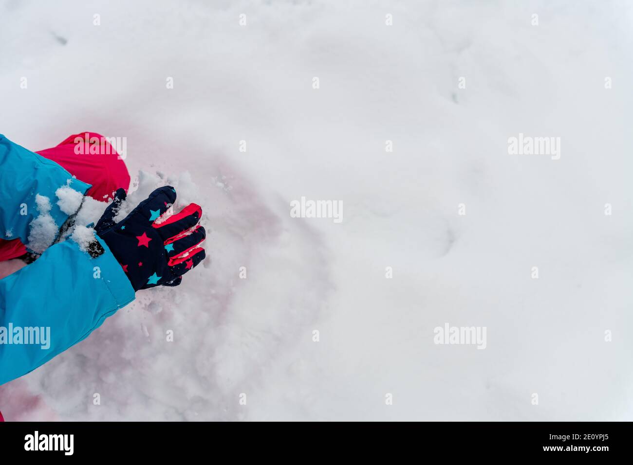 Child playing in the snow, gloves with stars. Making snow globe. Outdoor in winter landscape. Stock Photo