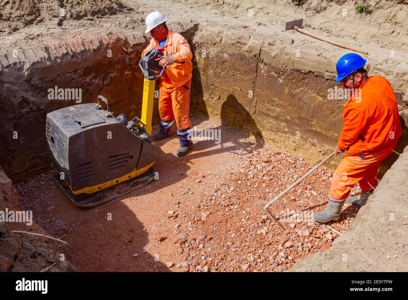 Workers are compacting gravel using vibration plate compactor machine