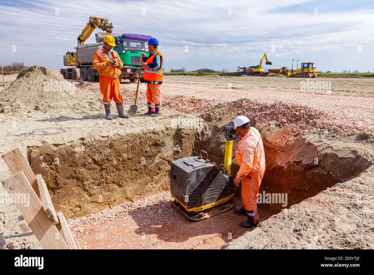 Worker is compacting gravel with vibration plate compactor machine in