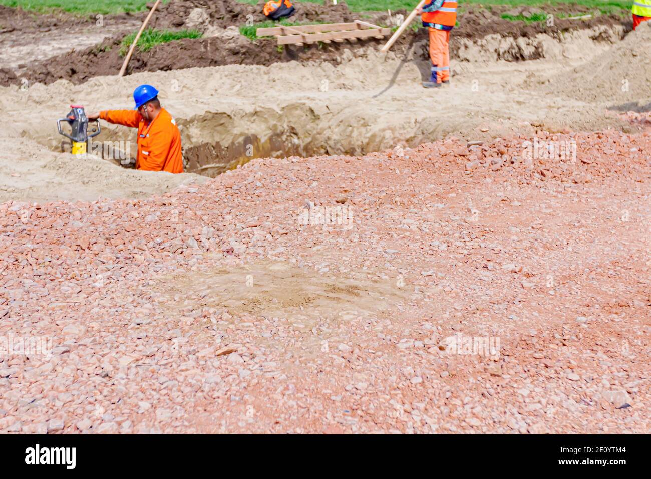 Worker is compacting gravel using vibration plate compactor machine in