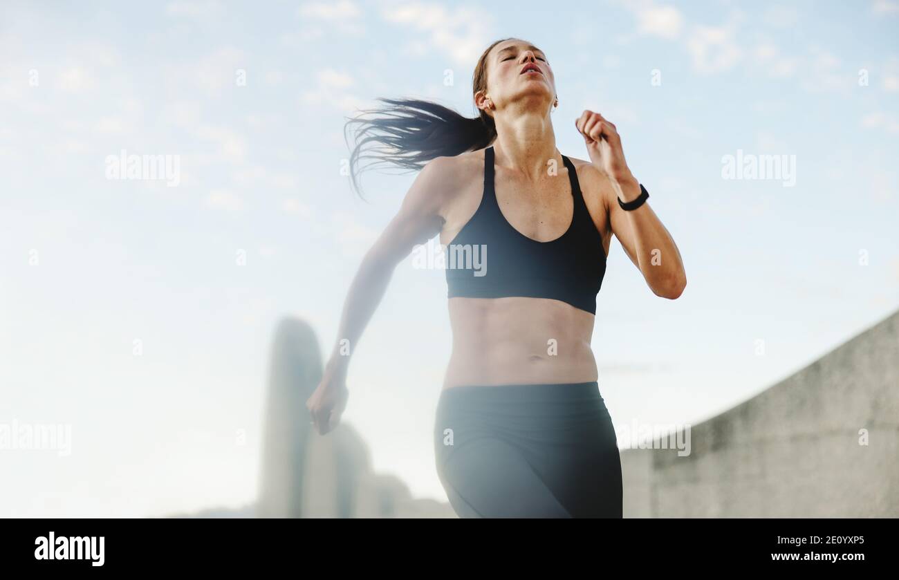 Athletic woman running outdoors in morning. Female in sportswear on a morning run. Stock Photo