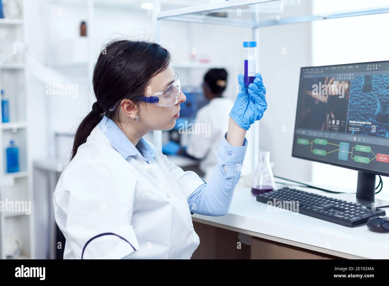 Chemist in professional medical lab looking at test tube with