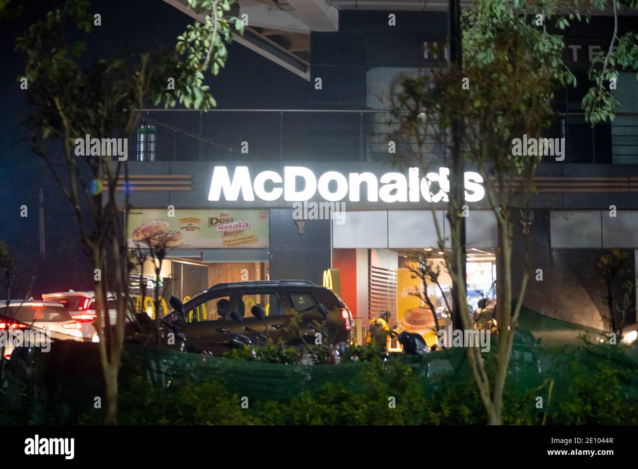 Night shot of lit Mcdonalds outlet at night showing cars lining up in front for burgers from this quick service restaurant Stock Photo