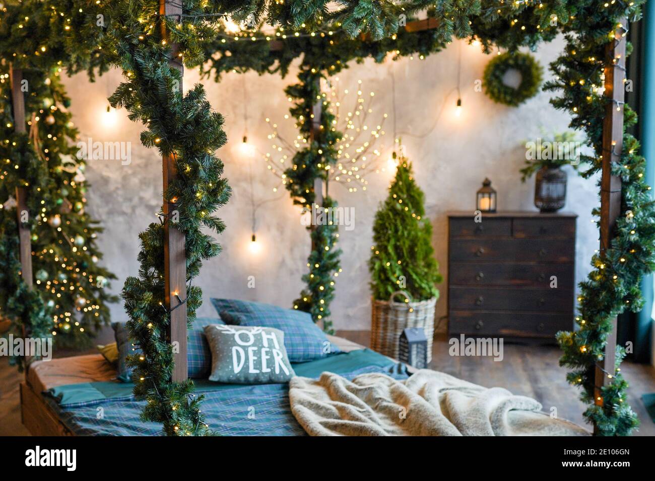 https://c8.alamy.com/comp/2E106GN/comfort-interior-and-holidays-concept-cozy-bedroom-with-bed-and-christmas-garland-lights-at-home-2E106GN.jpg