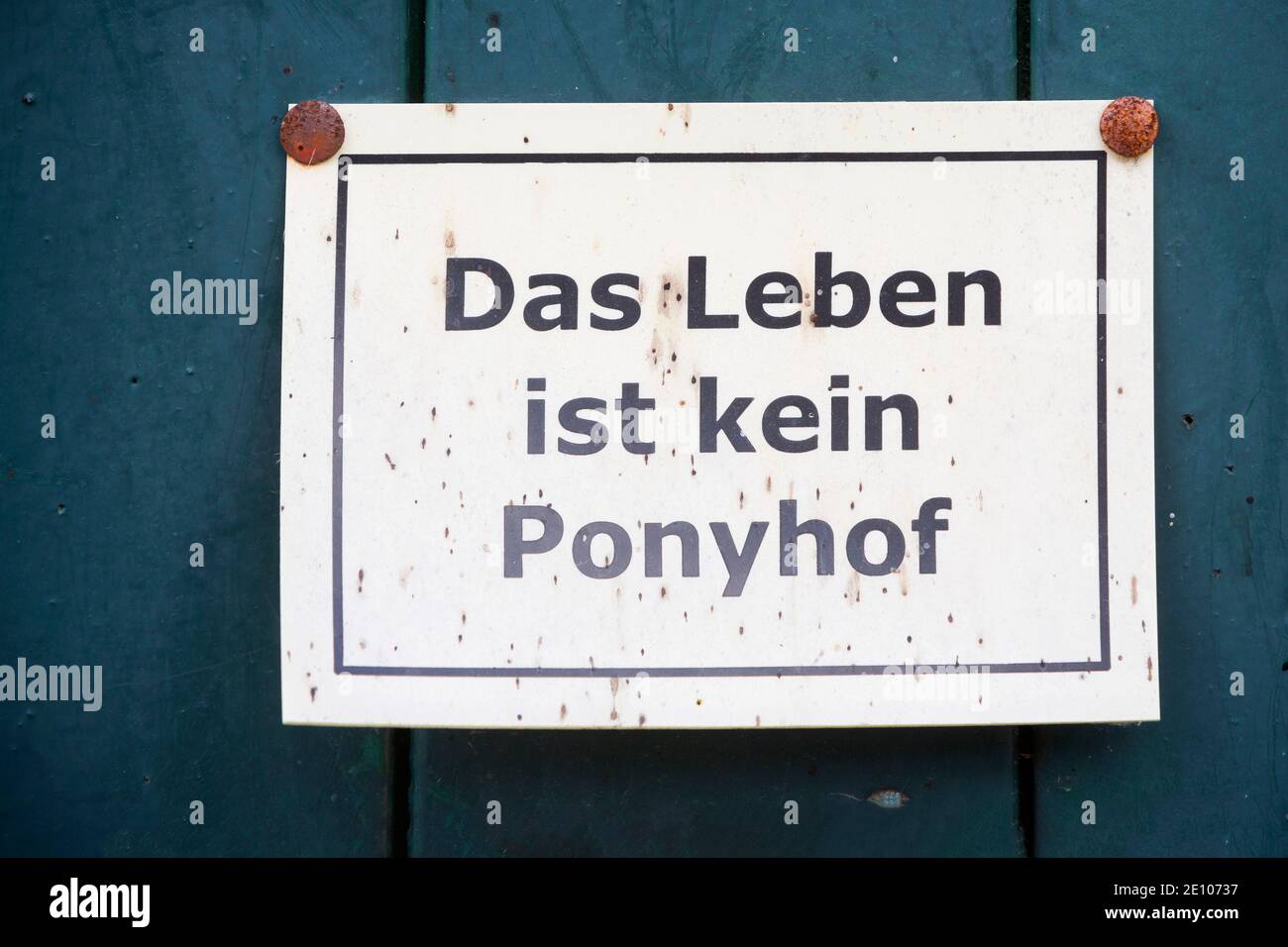Schild mit dem Spruch 'Das Leben ist kein Ponyhof' auf einem Ponyhof | Sign with the saying 'Life is not a pony farm' on a pony farm, which in German Stock Photo