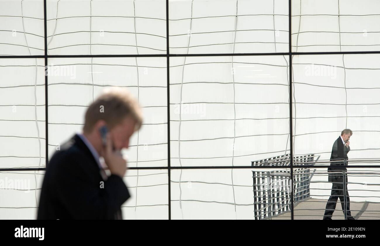Ein Mann telefoniert vor einer spiegelnden Wand | A man on the phone in front of a reflecting wall Stock Photo
