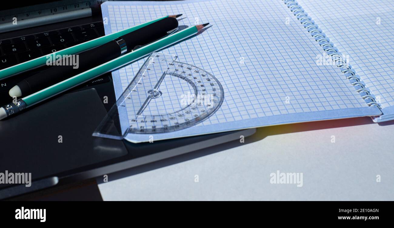 Stationery and squared notebook on laptop keyboard. Stock Photo
