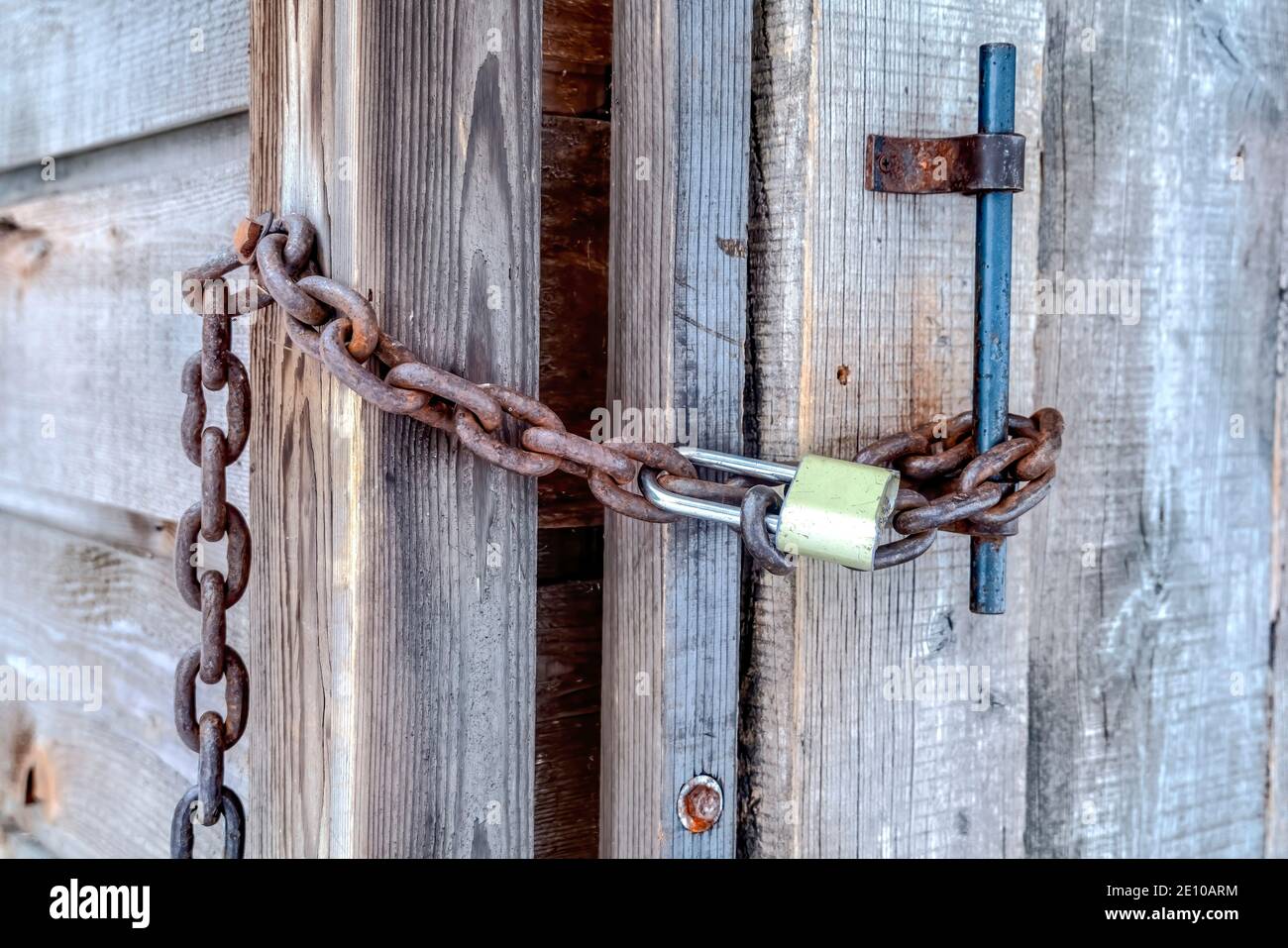 Padlock and rusty metal chain on the wooden door and handle of outdoor bathroom Stock Photo