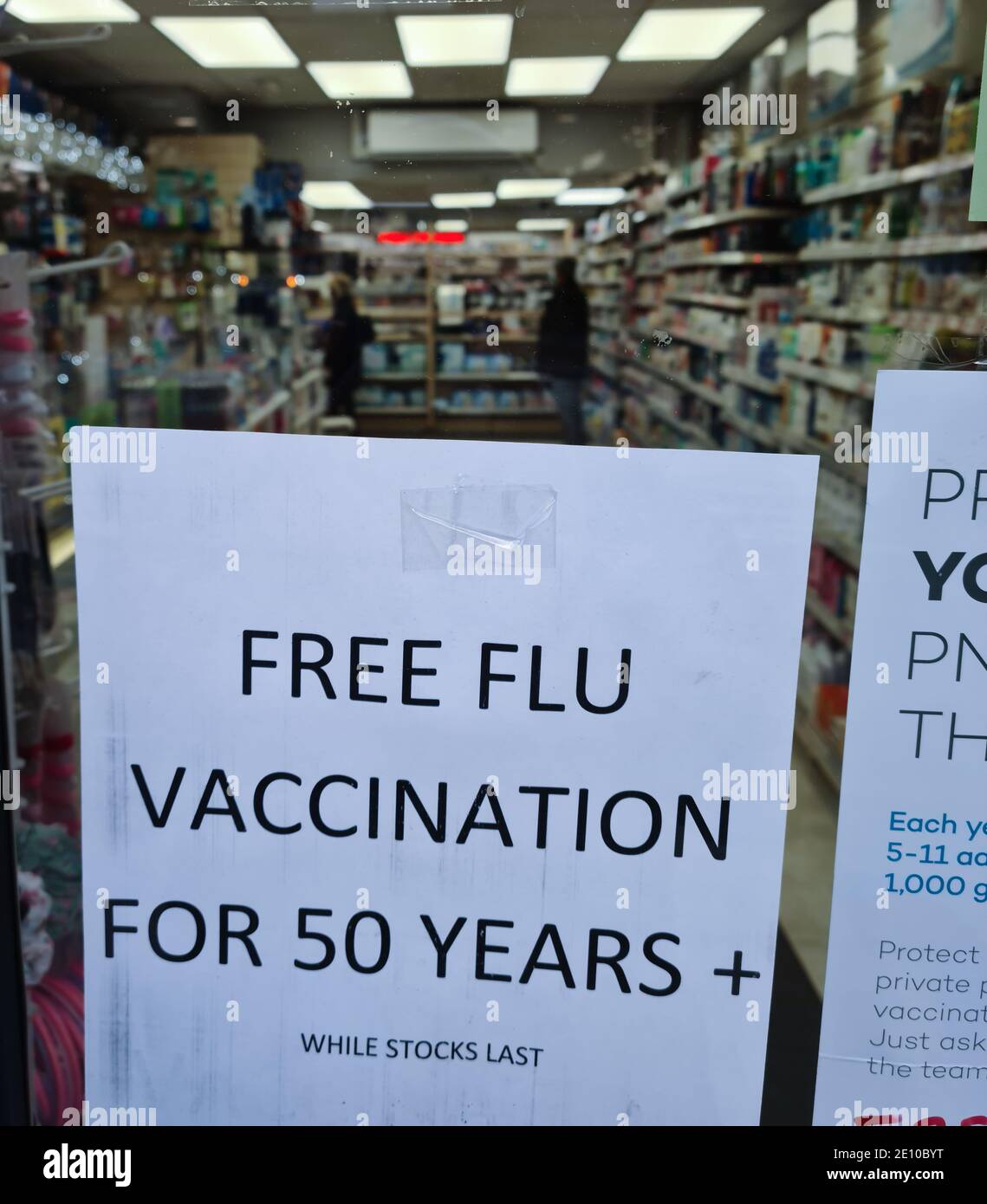 A notice in the window of a chemist, drug store offering over people over fifty free flu vaccination. Stock Photo