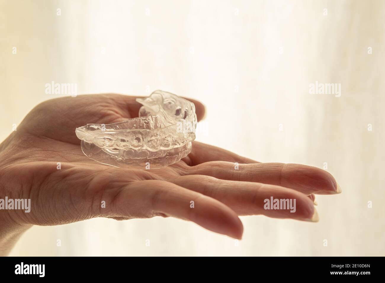 Teeth whitening mold on the palm of one hand, with a luminous