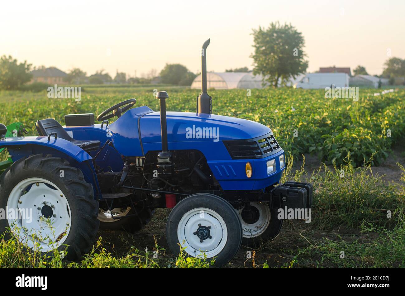 A farm tractor without a driver stands on a farm field at sunset
