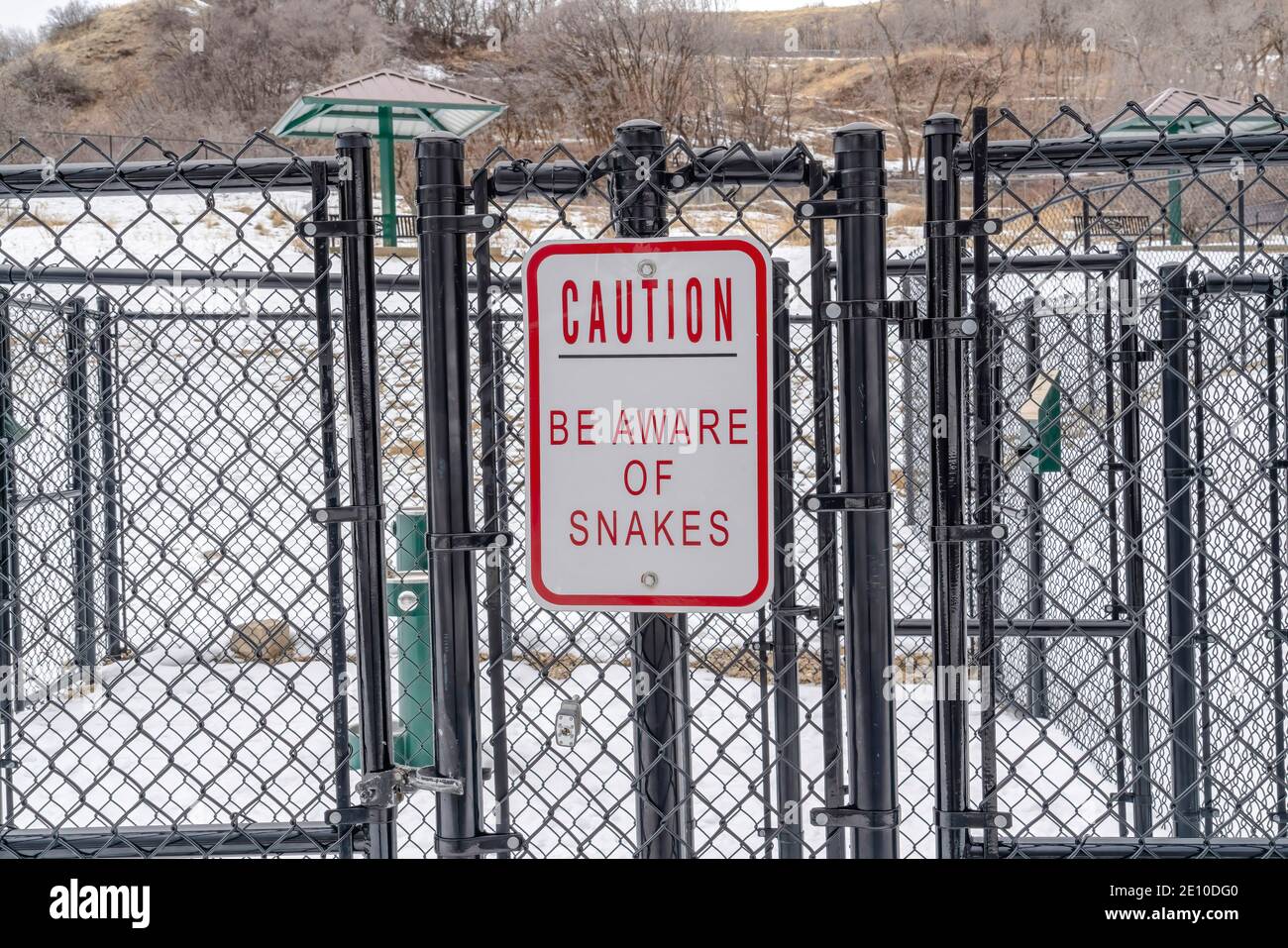 Caution Be Aware of Snakes sign on the chain link fence of a recreational park Stock Photo